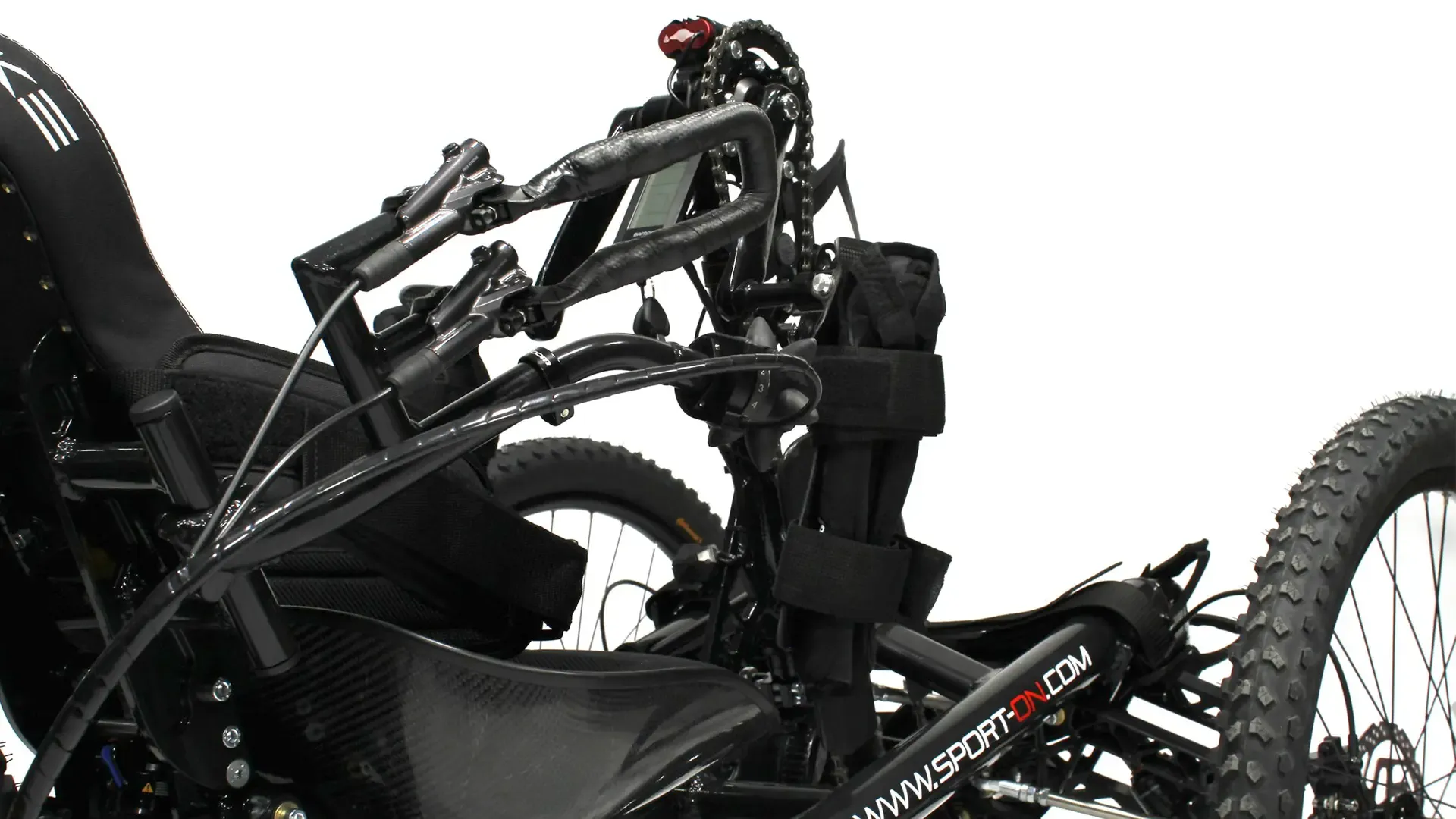 Close-up of black adaptive handcycle for disabled users, with pedals, seat, digital display; ideal for off-road outdoor activities.