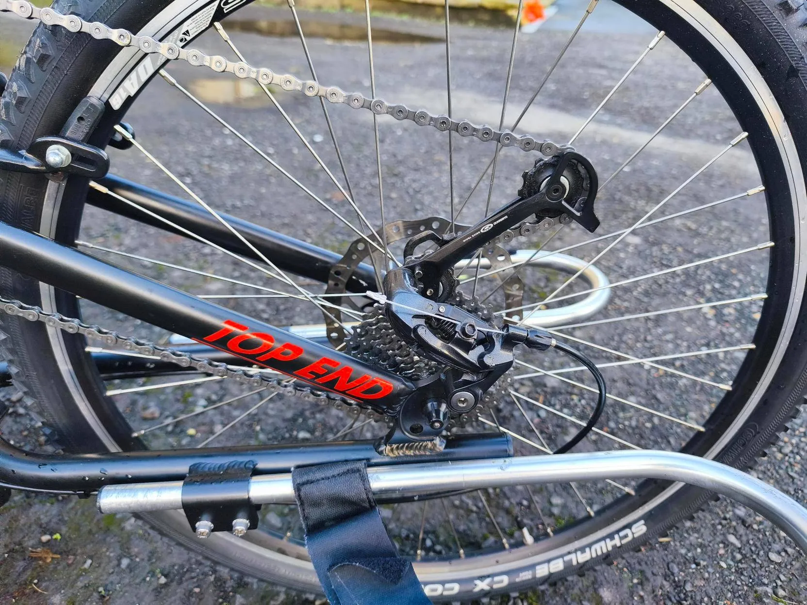 Handcycle rear wheel with derailleur and chain, used by disabled-friendly Community Interest Company for outdoor activities and cycling.