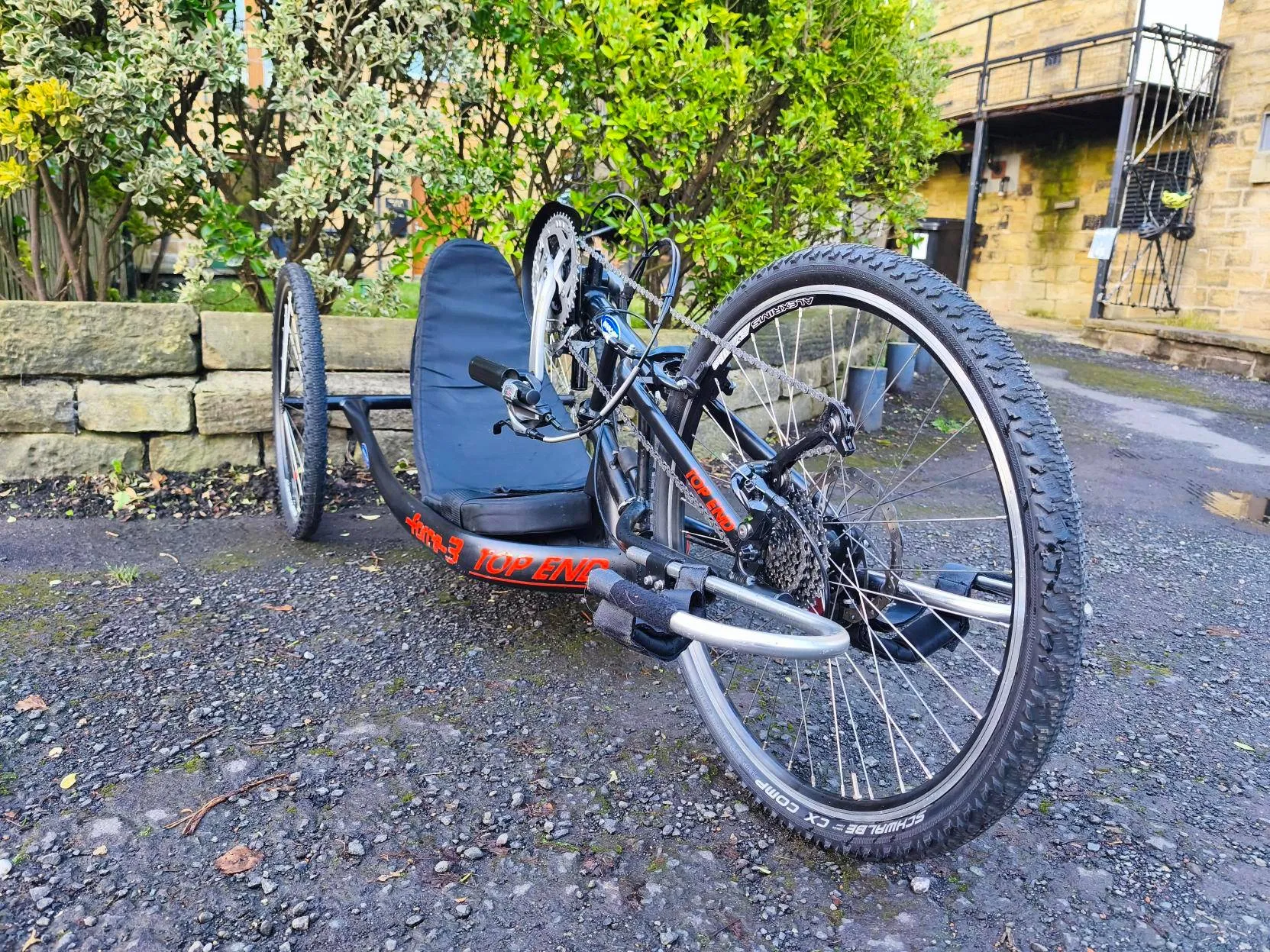 Accessible recumbent handcycle on gravel path, supporting disabled users in outdoor activities with our not-for-profit CIC.